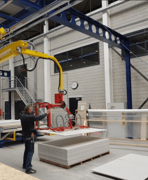 man using a vacuum lifter to load wood panels onto a pallet